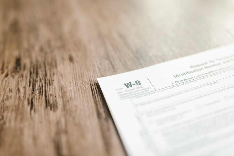A close-up of a W-9 tax form placed on a wooden desk, emphasizing paperwork and finance.