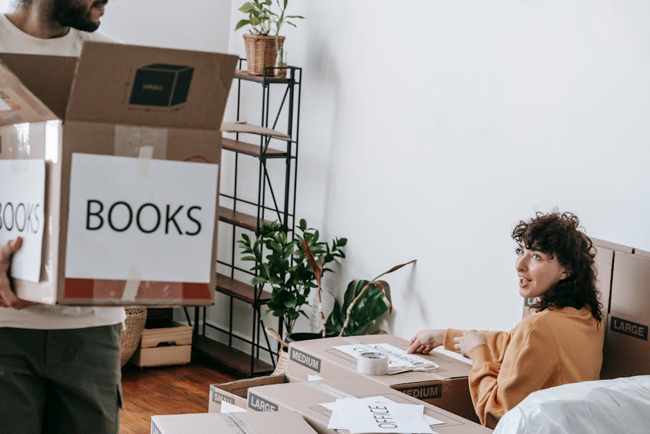 A couple packs boxes labeled books while preparing to move to a new home.