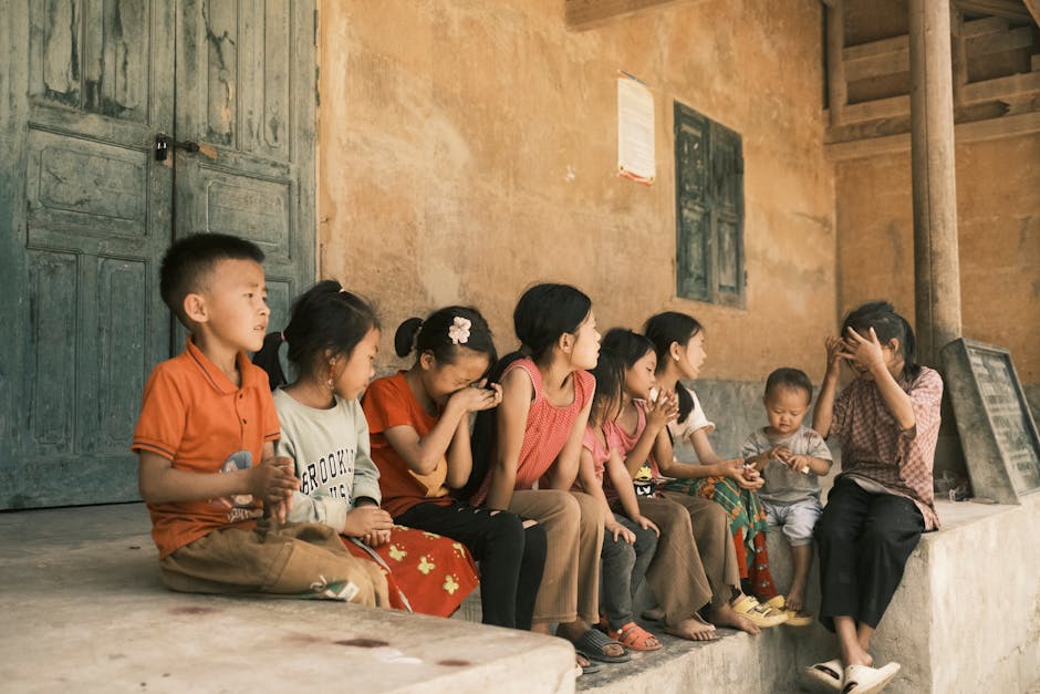 A group of children sitting on a rustic porch sharing a moment outdoors together.