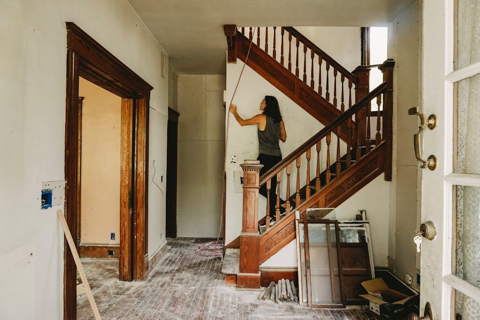 A woman working on home renovation featuring a wooden staircase.