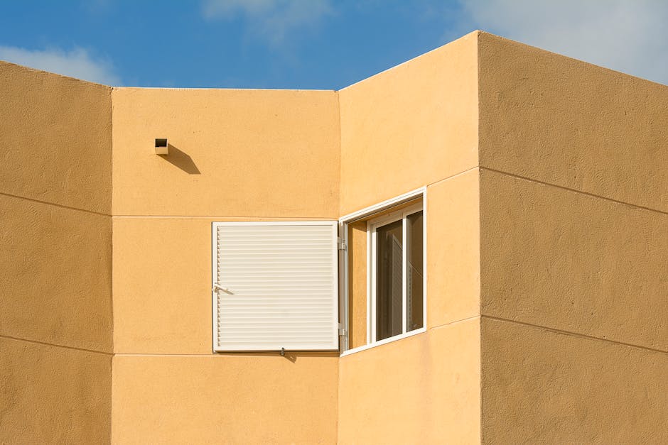 Close-up of a modern building facade with geometric lines and open shutters.
