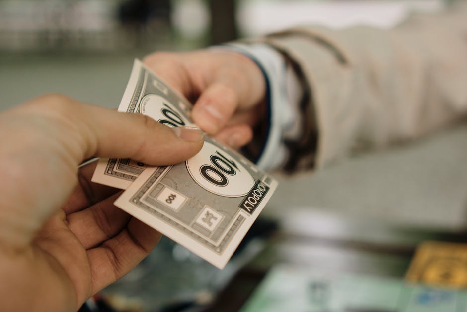 Close-up of two hands exchanging Monopoly money, symbolizing a financial transaction.