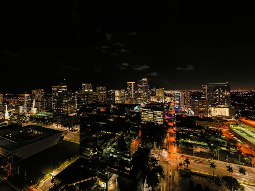 Drone view of asphalt roads and skyscrapers with glowing light and neon illumination in Fort Lauderdale at night