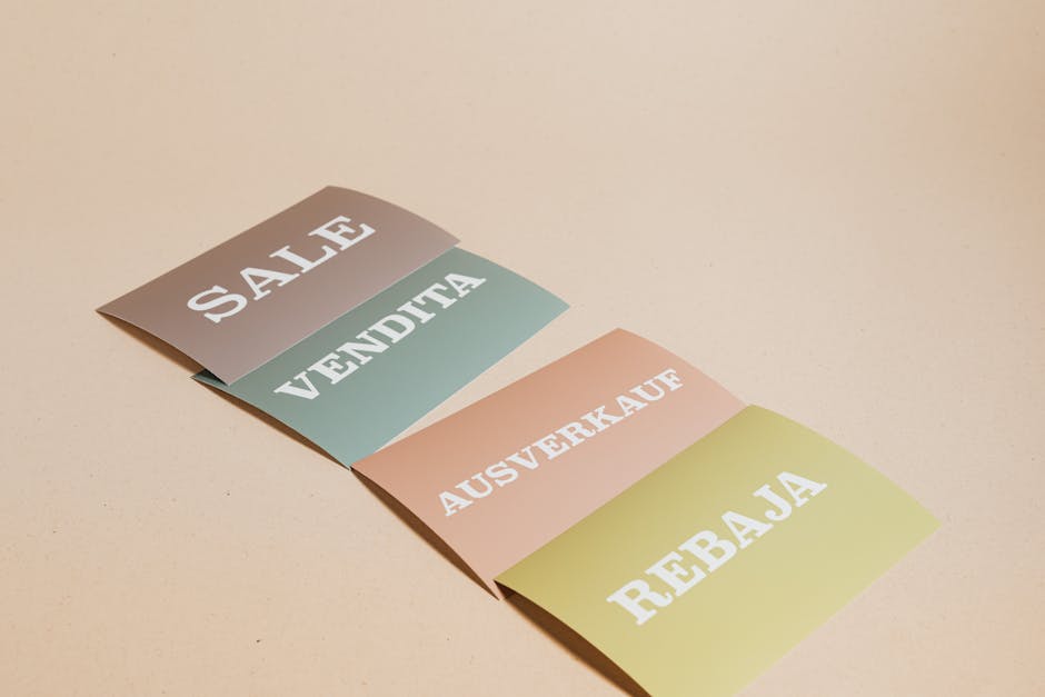 Four sale signs in different languages on a beige background, ideal for retail promotions.