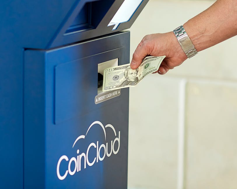 Hand inserting cash into a CoinCloud ATM, illustrating cryptocurrency exchange process.
