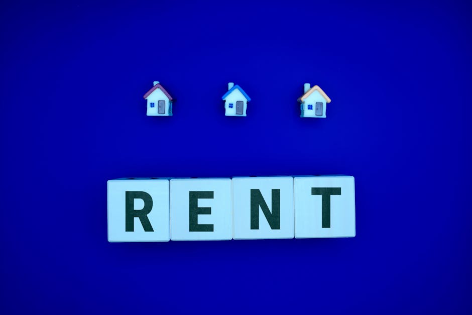 Miniature houses above letters spelling 'RENT' on a blue background, ideal for real estate themes.