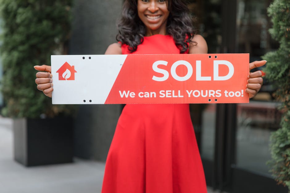 Smiling woman holding a 'Sold' sign, symbolizing successful real estate sales.